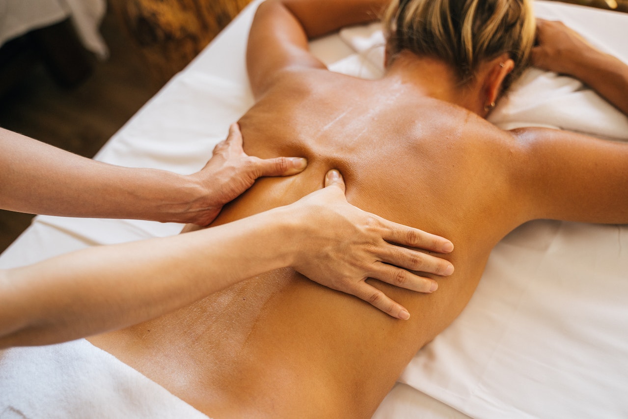 A Person Massaging a Client's Bare Back